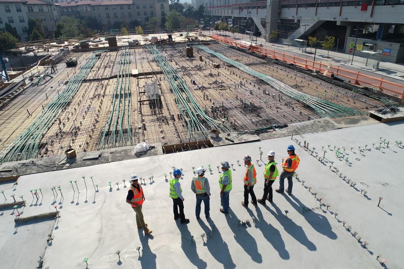 A construction crew standing on a freshly poured foundation