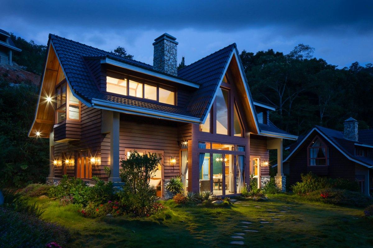 Warmly lit timber home set among tall trees at dusk